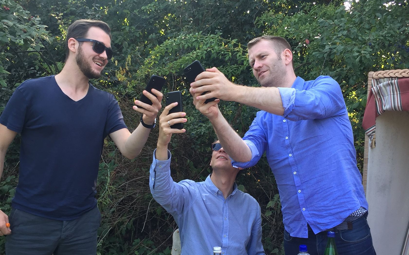 Drei Mitarbeiter zeigen das Handy in die Luft für einen besseren Empfang